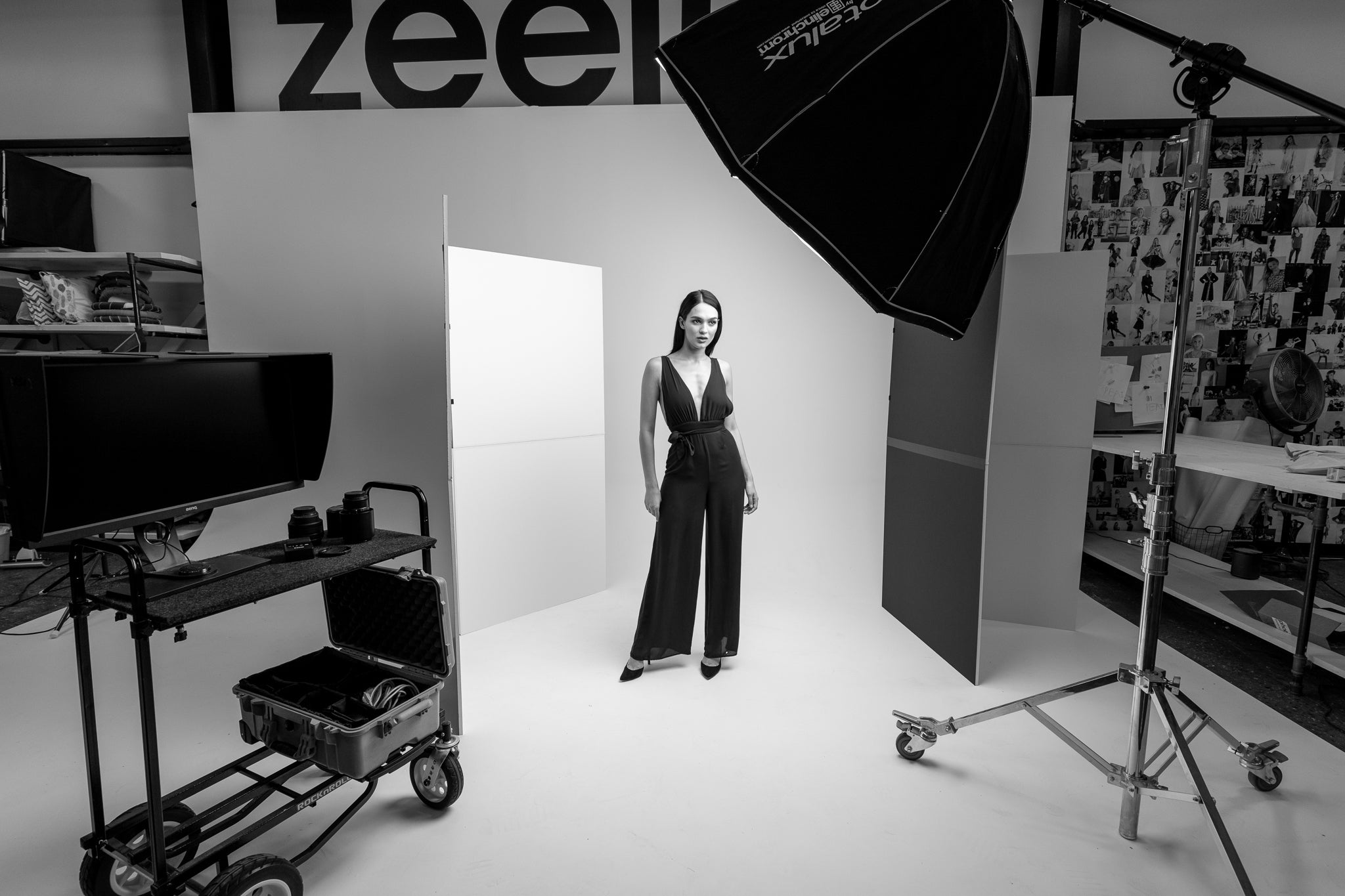 Photo studio portrait setup with model standing in front of white background under softbox lighting.
