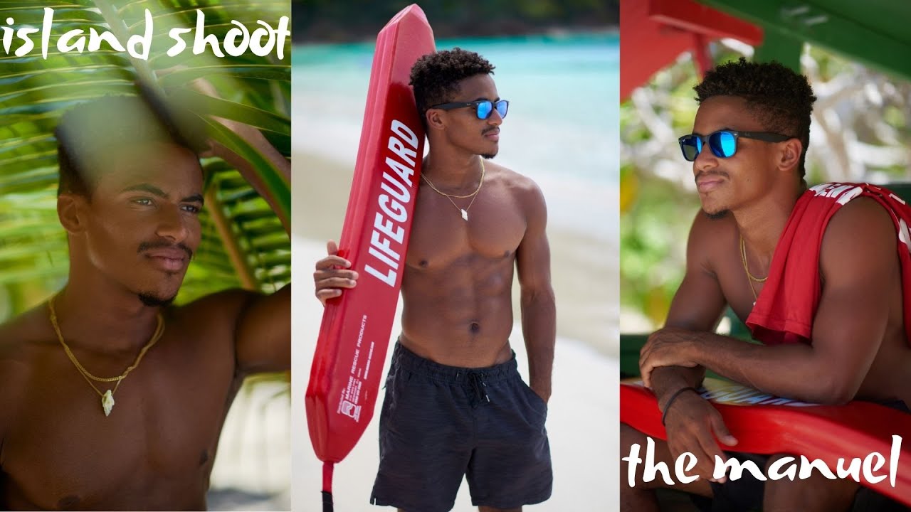 Attractive male lifeguard standing on a beach holding red rescue tube.